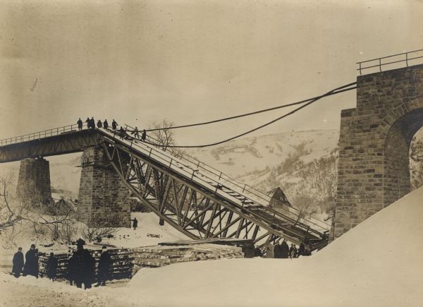 View of groups of Austrian soldiers, some standing at the base, some standing on an undamaged section, of a bridge destroyed by the Russians near the Dukla Pass in the Carpathian Mountains of Galicia.