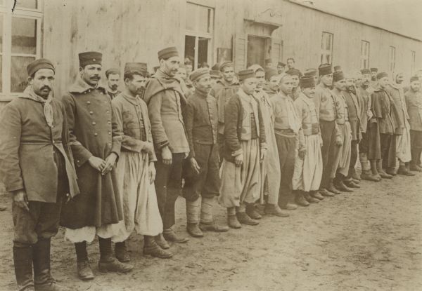 Group of French PoW's of varying nationalities and ethnicities standing in front of their barracks at the camp in Zossen.