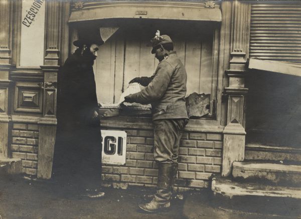 After the occupation and subsequent looting of a Galician city by the Russian Army, a Jewish merchant is selling his remaining wares to an Austrian soldier from the windowsill of his destroyed house.