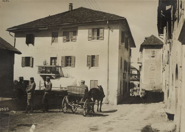 Soldiers relaxing in front of the Folgaria Hotel in Italy. Three men on the left are smoking cigarettes, and a man in the center is sitting in a horse-drawn cart.
