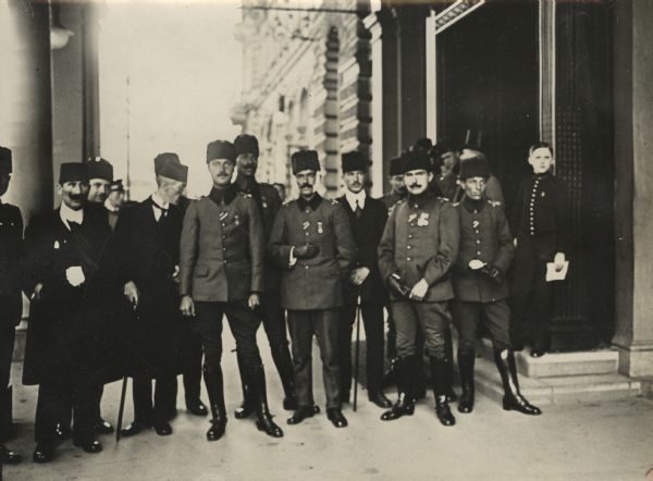 Turkish officers convalescing in Berlin sometime after the Ottoman Empire entered the war on the side of Germany in October 1914. The group of men are standing on a sidewalk near the entrance to a building.