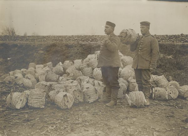 Two men at a barbed wire depot behind the front. 