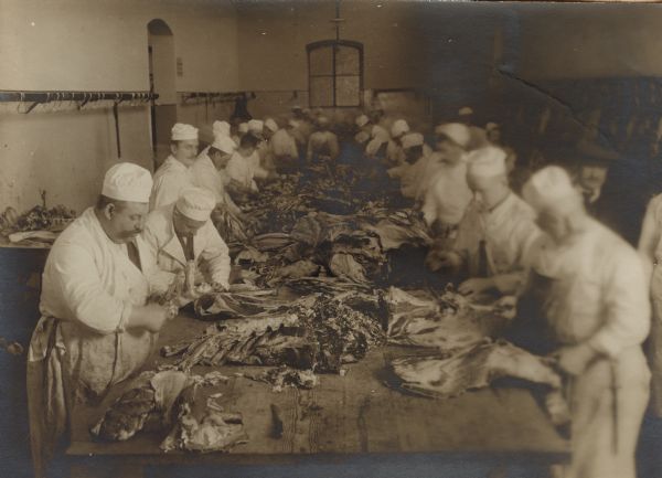 De-boning meat for goulash in the kitchen for the soldiers to consume. 