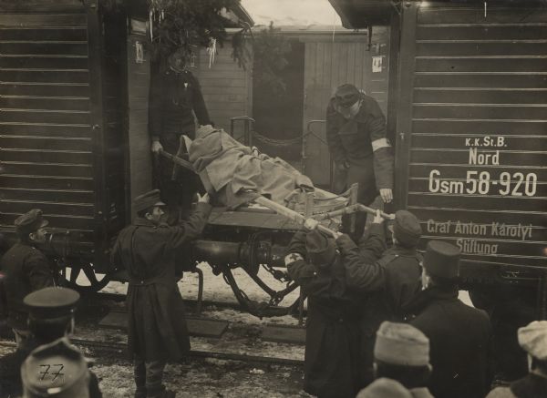 Wounded Austrian soldiers being loaded onto train cars.