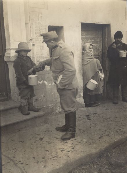Kindheartedness. Austrian soldier sharing his rations with a hungry child.
