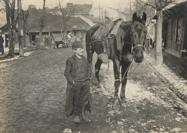 A Jewish child in Galicia is holding an Austrian cavalryman's horse. 