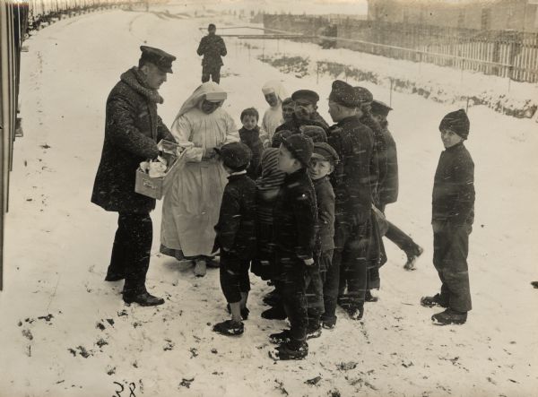 Hungry children receiving Zwieback (crisp bread) from a warm-hearted Red Cross in Lodz, in order to partially relieve their hunger. 