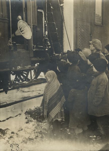 Group of children standing in front of a hospital train in Lodz listening to a gramophone set up to play music while the train was in the station.