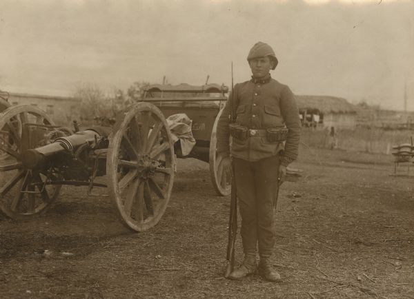Turkish soldier on guard in front of an artillery piece.