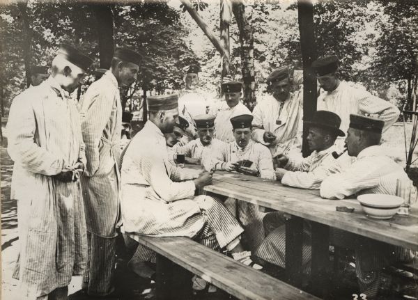 The first wounded soldiers in Berlin, playing skat outdoors at a long table.