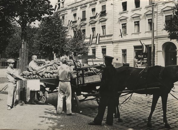 A common sight in wartime. Delivery of loaves of bread on large freight wagons.