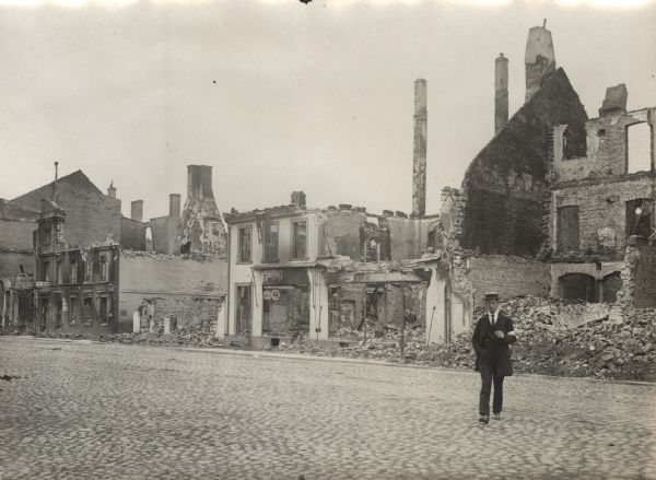 Scene of destroyed and burned buildings. A man is walking across the street.