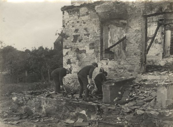 Civilians searching in building ruins for their possessions.