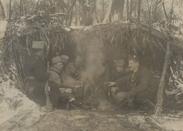 Austrian soldiers gatherered around fire in a makeshift hut.