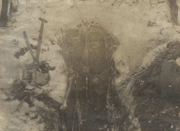 Soldiers hunkering down in a trench on a cold winter morning.