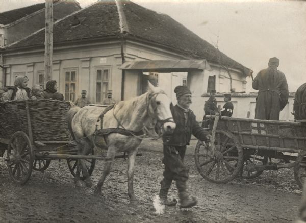 Serbian refugees walking through muddy streets with wagons and goods.
