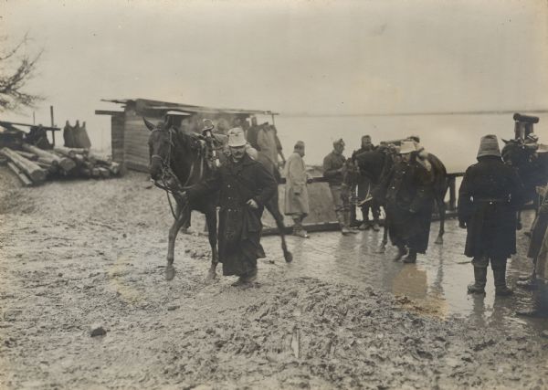 Soldiers leading horses and supplies to the bridge guard.