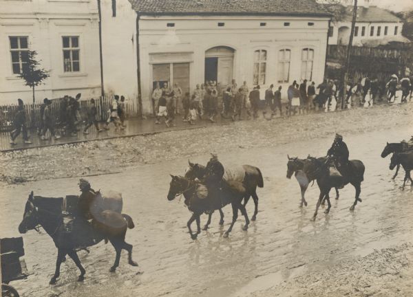 Elevated view of Austrian soldiers riding through Sabac with Serbian prisoners in the background.