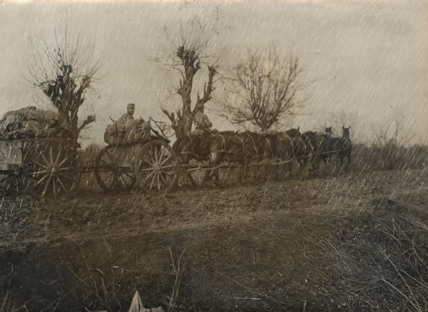 Men with wagons pulling supplies and artillery through stormy Serbia.