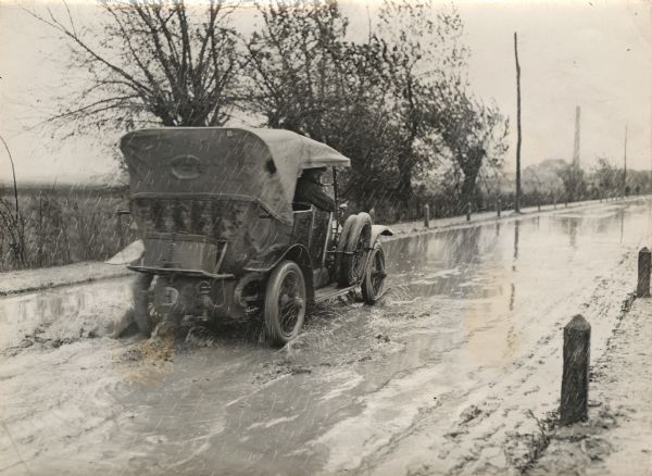 Men in a Austrian military automobile driving through the mud to deliver supplies to the front.