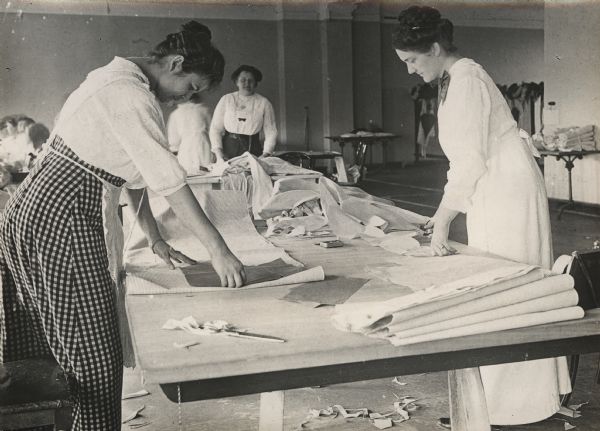 Female volunteers cutting fabric.