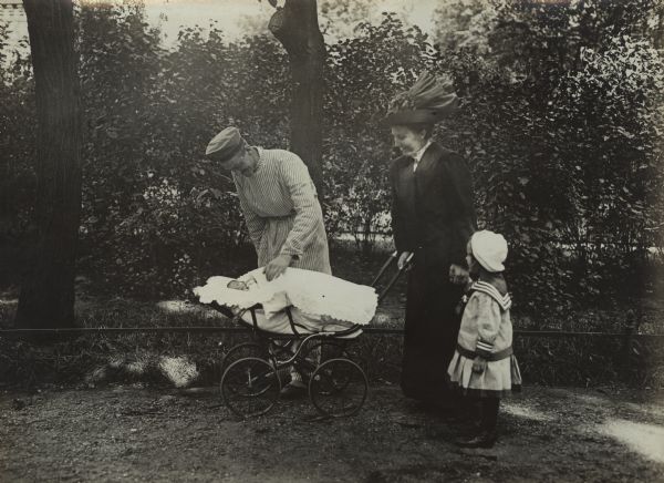The first visiting day at the garrison hospital to see the wounded soldier. His wife, daughter, and infant son in a baby carriage, are visiting him outdoors.