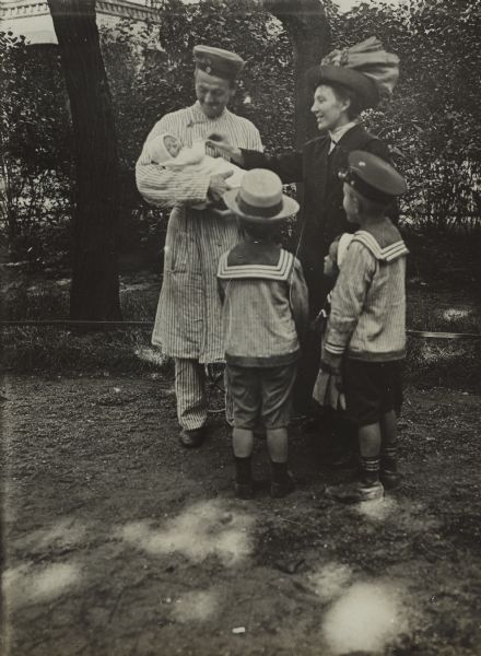 The first visiting day at the garrison hospital to see the wounded soldier. His wife, three children, and infant son are visiting him outdoors.