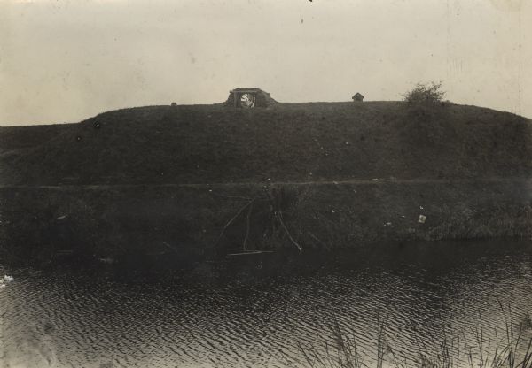 Searchlight positioned on a fort in Antwerp in order to light a section of railroad track. Water is in the foreground.
