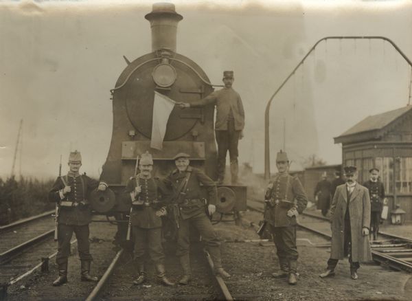 The first neutral train carrying returning refugees is pulling into the Merxen station in Antwerp. Soldiers are posing in front of the engine.