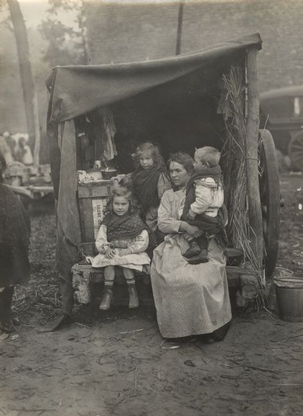 Refugees sitting at the back of a wagon that has become their home.