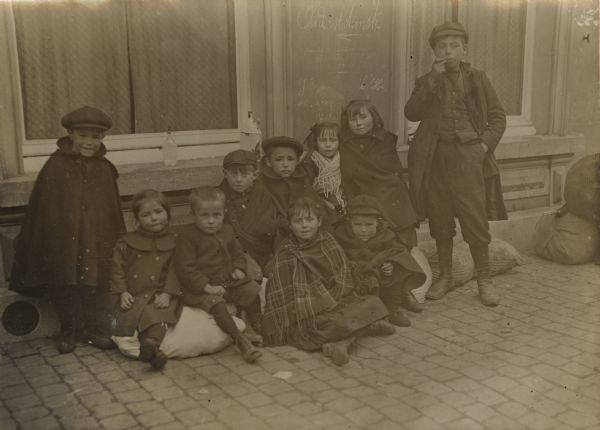 Belgian refugee children posing together for the camera on the sidewalk.