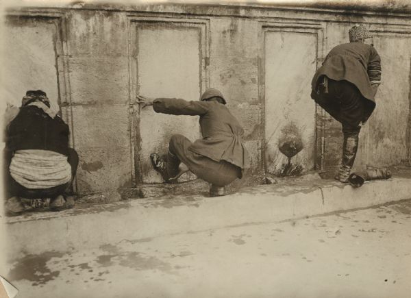 Turkish men washing their footware at an outdoor fountain.