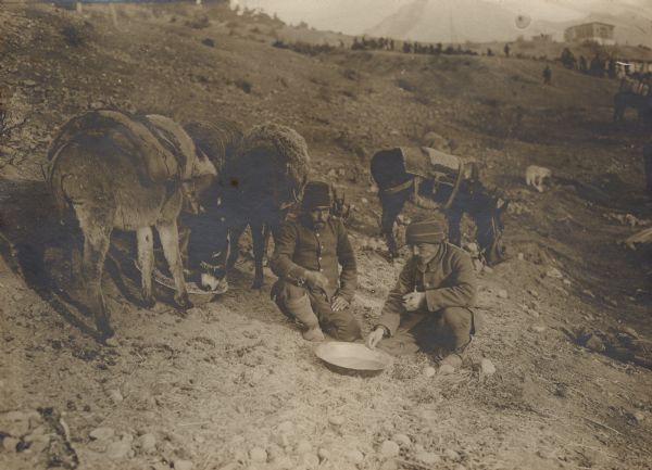 At rest in the mountains. Troops are eating out of a common bowl, and three donkeys are eating out of another bowl on the left. 