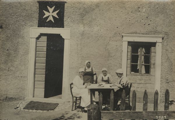 Nursing sisters from Vienna serving with the surgical group of the Sovereign Order of the Maltese Cross. They are sitting and standing at a table in front of a field hospital on the southern battlefront. 