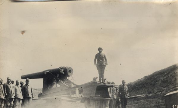 Turkish soldiers posing for a portrait on and around a cannon. 