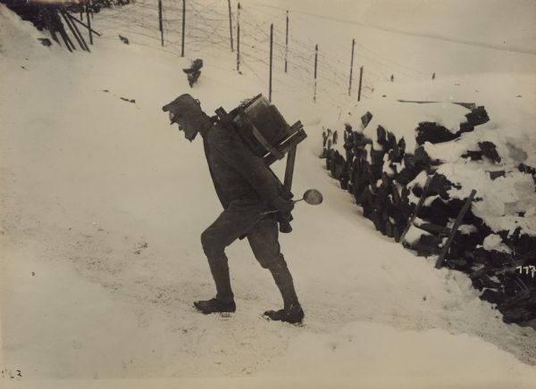 Provisioning supplies and munitions to soldiers fighting against the enemy and nature at over 3000 meters in elevation can only be accomplished through human effort. A soldier is hauling a cooked food canister on his back up a slope. 