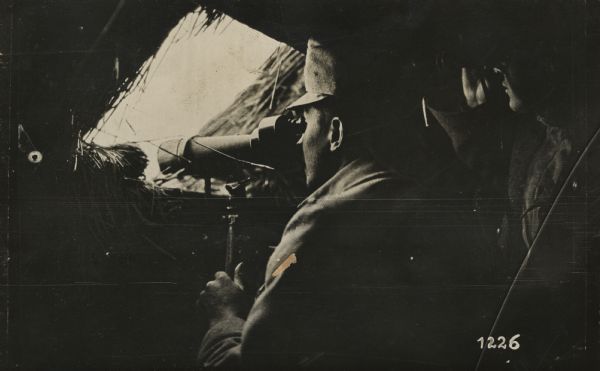 Austrian soldiers observing Serbian troop movements from the attic window of a hut. 