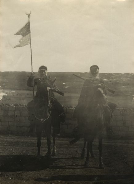 Senussi volunteers on horseback. The fighter on the left is holding a holy banner. 