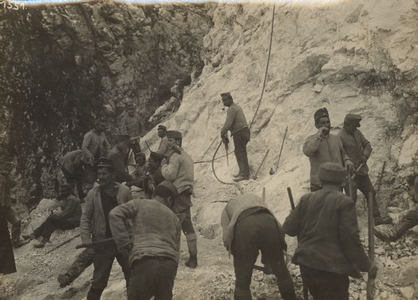 Repair work on Mount Lovcen to repair war damage. caused by the Montenegrans. Soldiers drilling into rock on the side of the mountains. 