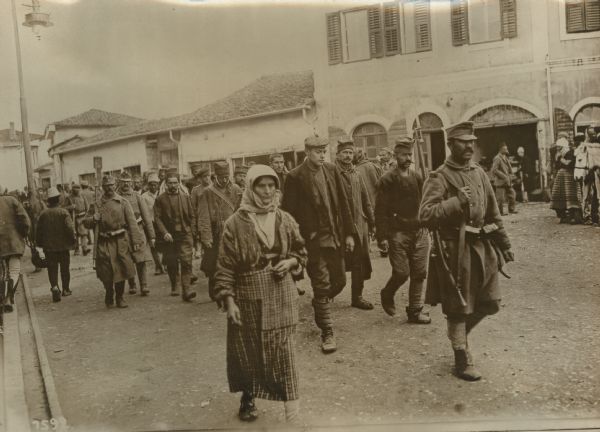 Serbian prisoners in Skutari under guard going to receive a meal.