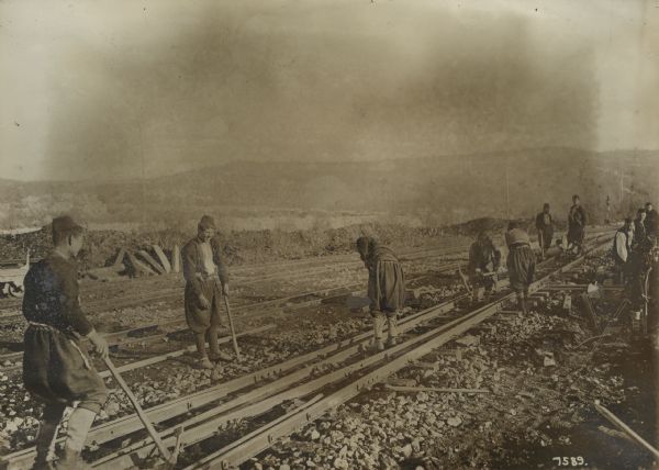 Civilians working on improving the railroad track bed.