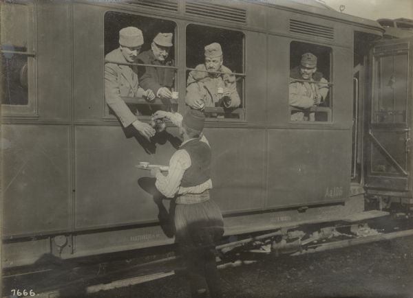 Buying coffee at a Bosnian train station. Austrian soldiers in a train car are purchasing coffee from a street vendor.