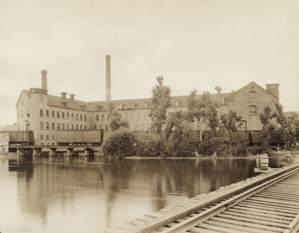 View across water from railroad bridge towards the Neenah paper mill. 