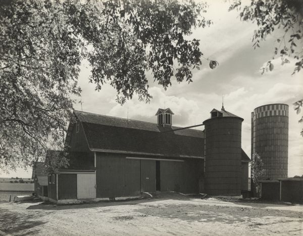 View of a barn with two silos on the right. 