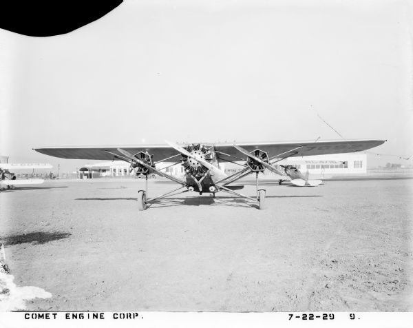 Front view of a trimotor Bach 3-CT-4 manufactured by the Bach Aircraft Company of Santa Monica, California. The company was formed in 1927 by L. Morton Bach, an aviator whose unique line of Air Yachts was constructed almost entirely of wood with steel fittings, undercarriage and struts. The 3-CT-4 Air Yacht, typical of this line, was a high-wing cantilever monoplane powered by a large engine in the nose of the aircraft and two smaller "helper" engines under the wings in nacelles. It was powered by one Pratt & Whitney Wasp 450 hp air-cooled engine and by two Comet 100 hp (112 kW) engines, designed by the Comet Engine Corporation. Gisholt Machine Company purchased the the Comet factory in Oakland, California and moved it to Madison, Wisconsin in 1929.

The plane, with registration number 7092, is parked at Hangar No. 1 on the Oakland air field. Unseen decal text on the body reads: "West Coast Air Transport, Co. Owned and Operated by Union Air Lines." This W.C.A.T. Co. was incorporated in Portland, Oregon in 1928 to offer scheduled passenger and cargo flights over a multi-stop route from Seattle down to San Francisco.
