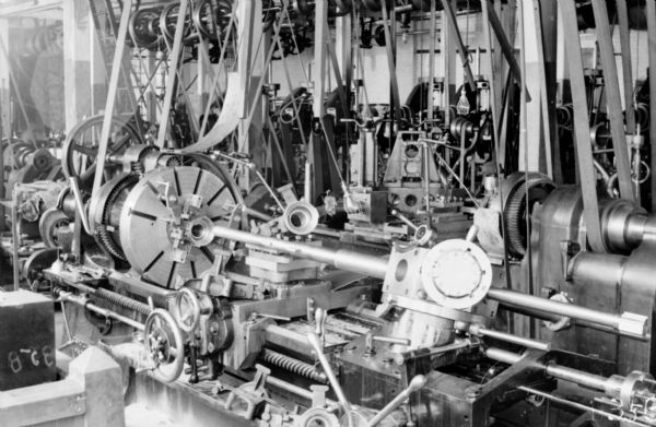 View of a 28" Old Type Gisholt turret lathe at the Packard Motor Car Company factory. This lathe machined a brake band support.

The original envelope housing this photograph was inscribed with the following information: "Showing centering device on top of turret for truing up large end of piece by putting it on boring bar and holding piece in position while chucking."