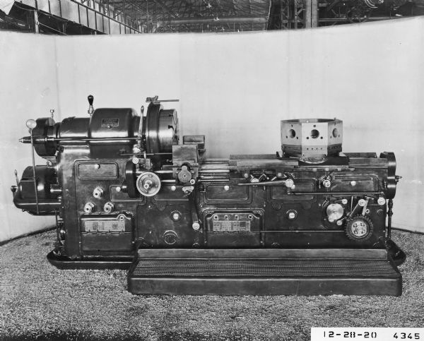 This automatic turret lathe, photographed inside the factory shop in front of a sweep, was manufactured in 20" and 30" sizes. Produced by 1920, promotional material for the Gisholt Machine Company states that "for duplication of machined castings and forgings in large quantities, the Gisholt Automatic Turret Lathe is even more rapid than he hand operated machine, and its assembly of multiple cutting tools do their work more quickly and surely." Generally one operator ran three or more machines, "reducing the cost for labor to a fraction of that required for hand operated machines."