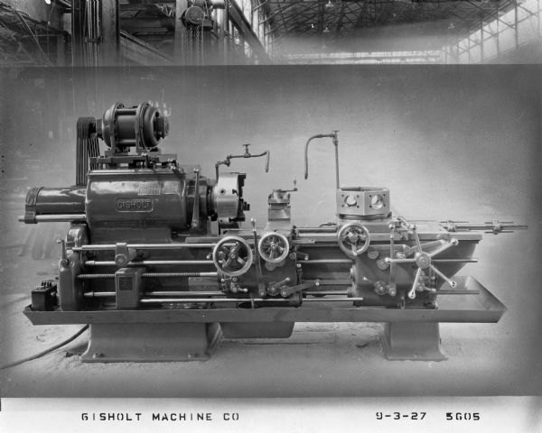 Automatic saddle lathe in the factory shop. Promotional material for the Gisholt Machine Company states that "for duplication of machined castings and forgings in large quantities, the Gisholt Automatic Turret Lathe is even more rapid than the hand operated machine, and its assembly of multiple cutting tools do their work more quickly and surely." Generally one operator ran three or more machines, "reducing the cost for labor to a fraction of that required for hand operated machines."