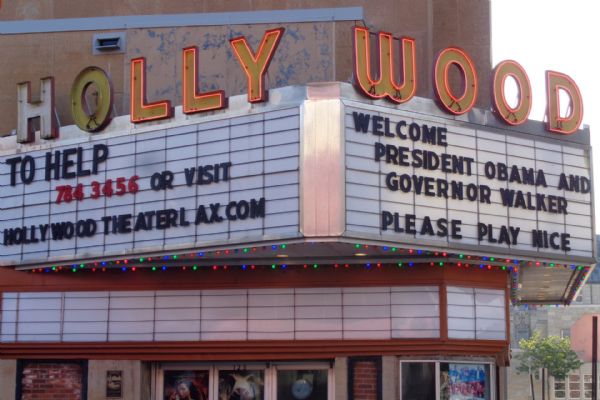 View of the marquee of the Hollywood Theater. On the left side it reads: "To help 784 3456 or visit hollywood theater lax.com," and on the right side it reads: "Welcome President Obama and Governor Walker, please play nice."