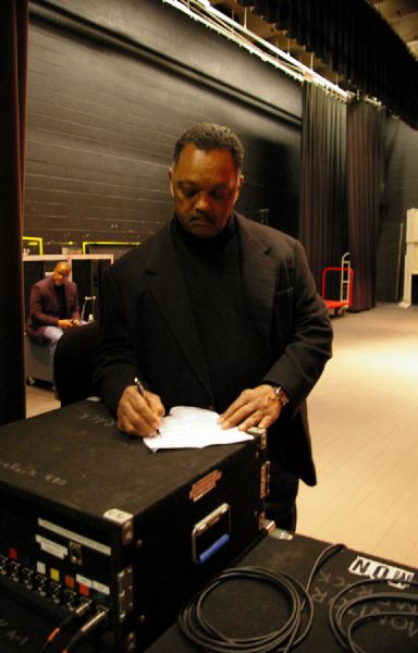 Jesse Jackson is standing backstage and editing his speech on top of sound equipment at UW-LaCrosse.